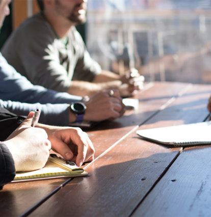 group of business people sitting around wood meeting table