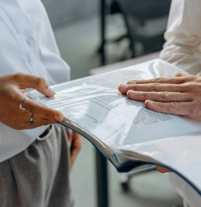 two people standing next to each other holding a report